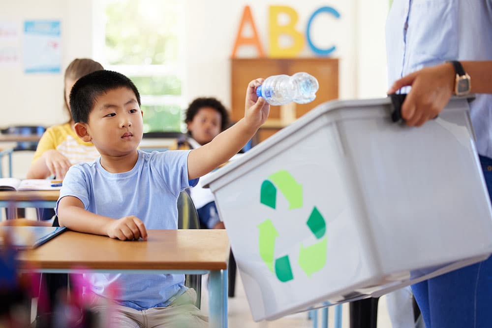 kid recycling water bottle at school